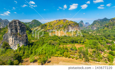Dramatic Limestone Peaks Over Verdant Countryside in Laos Dramatic Limestone Peaks Over Verdant Countryside in Laos 143677220