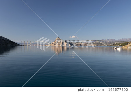 Krka Bridge Arch Bridge Structure Over Calm Blue Water with Clear Sky Krka Bridge Arch Bridge Structure Over Calm Blue Water with Clear Sky 143677500