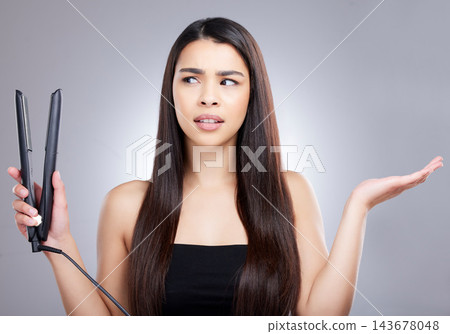 Hair care, flat iron and confused woman in studio for hairstyle, keratin treatment or cosmetics on gray background. Salon, beauty and model with doubt for grooming, texture or electric straightener Hair care, flat iron and confused woman in studio for hairstyle, keratin treatment or cosmetics on gray background. Salon, beauty and model with doubt for grooming, texture or electric straightener 143678048