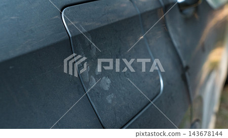 Dust covered dark car body with visible road grime and smudged surface details in a close up automotive exterior view Dust covered dark car body with visible road grime and smudged surface details in a close up automotive exterior view 143678144