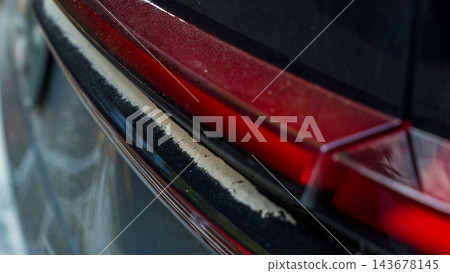 Close up of dust coated red car tail light and rear trim after travel on an unpaved road, automotive exterior detail Close up of dust coated red car tail light and rear trim after travel on an unpaved road, automotive exterior detail 143678145