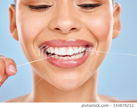 Dental floss, woman and wellness in studio for healthy gums, teeth whitening or morning routine on blue background. Closeup, oral care and model for fresh breath, remove plaque or mouth hygiene Dental floss, woman and wellness in studio for healthy gums, teeth whitening or morning routine on blue background. Closeup, oral care and model for fresh breath, remove plaque or mouth hygiene 143678252