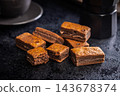 Close-Up Stack Of Chewy Chocolate Brownies With Crumbly Texture On Dark Surface 143678374