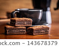 Stacked Chocolate Brownies With Coffee Mug In Cozy Cafe Setting, Close-Up Dessert Photo 143678379