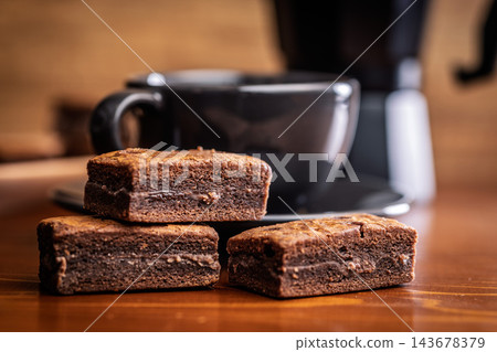 Stacked Chocolate Brownies With Coffee Mug In Cozy Cafe Setting, Close-Up Dessert Photo Stacked Chocolate Brownies With Coffee Mug In Cozy Cafe Setting, Close-Up Dessert Photo 143678379