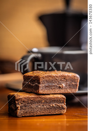 Stacked Chocolate Brownies With Coffee Mug In Cozy Cafe Setting, Close-Up Dessert Photo Stacked Chocolate Brownies With Coffee Mug In Cozy Cafe Setting, Close-Up Dessert Photo 143678380