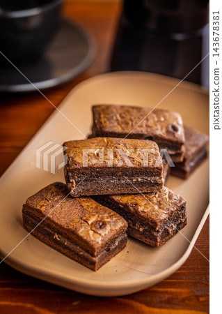 Stacked Homemade Chocolate Brownies on a Plate with Coffee Cup Close-Up in Cozy Cafe Setting Stacked Homemade Chocolate Brownies on a Plate with Coffee Cup Close-Up in Cozy Cafe Setting 143678381
