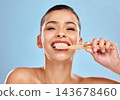 Woman, portrait and brushing teeth in studio with hand, dental care and mouth wellness for hygiene. Bamboo, toothbrush and eco friendly product on blue background, cleaning and happy for oral health 143678460