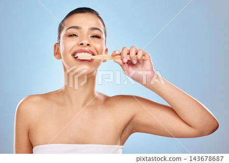 Woman, portrait and brushing teeth in studio for cleaning, dental care and mouth wellness for hygiene. Bamboo, toothbrush and eco friendly product on blue background, fresh breath and oral health Woman, portrait and brushing teeth in studio for cleaning, dental care and mouth wellness for hygiene. Bamboo, toothbrush and eco friendly product on blue background, fresh breath and oral health 143678687