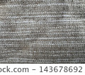 Rough woven textile close-up with tan fibrous yarns and thin white horizontal stripes, full frame natural-look fabric background 143678692