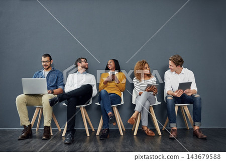 Business people, recruitment and waiting room in conversation or networking for job search opportunity. Group of employees or candidate in queue, chair and online technology by gray wall background Business people, recruitment and waiting room in conversation or networking for job search opportunity. Group of employees or candidate in queue, chair and online technology by gray wall background 143679588