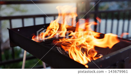 Bbq, flame and grill with fire in backyard for party, holiday or weekend lunch with heat at home or patio. Outdoor barbecue for meat, steak or cooking with hot metal stand on porch to prepare meal 143679961