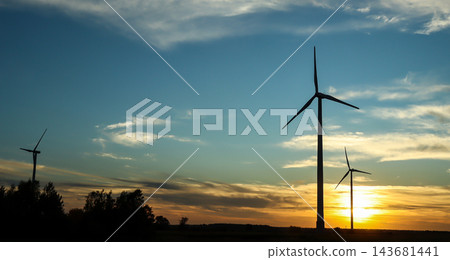 Silhouettes of wind turbines in field at sunset with blue sky and clouds, large copy space. Concept of renewable energy, green power, sustainability, climate change, energy transition Silhouettes of wind turbines in field at sunset with blue sky and clouds, large copy space. Concept of renewable energy, green power, sustainability, climate change, energy transition 143681441