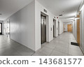 Modern apartment building corridor with steel elevator doors, white walls, and apartment entrance doors. 143681577