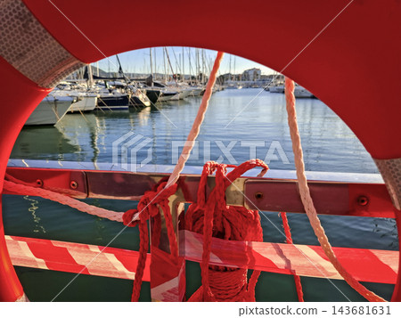 View of Marina and Yachts Framed Through Red Lifebuoy 143681631