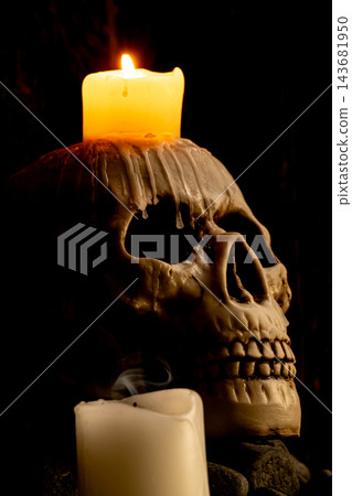 Halloween human skull, an image of a human skull with candles in a very old rustic wooden setting, selective focus. Halloween human skull, an image of a human skull with candles in a very old rustic wooden setting, selective focus. 143681950