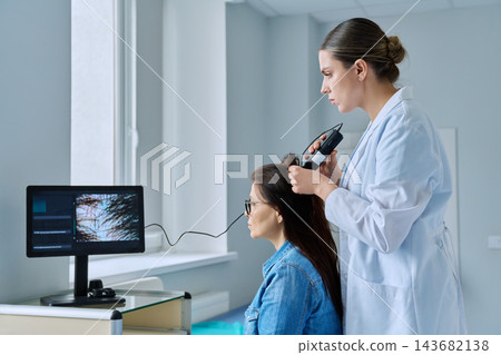 Trichologist examining patient hair and scalp using trichoscope in medical clinic Trichologist examining patient hair and scalp using trichoscope in medical clinic 143682138