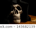 Human skull for Halloween, an image of a human skull in a macabre setting with fabric draped over the head to represent death, selective focus. 143682139