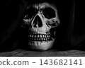 Human skull for Halloween, an image of a human skull in a macabre setting with fabric draped over the head to represent death, selective focus. 143682141