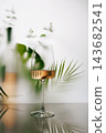 Vertical Rose Wine Glass with Tropical Foliage and Blurred Bottle 143682541