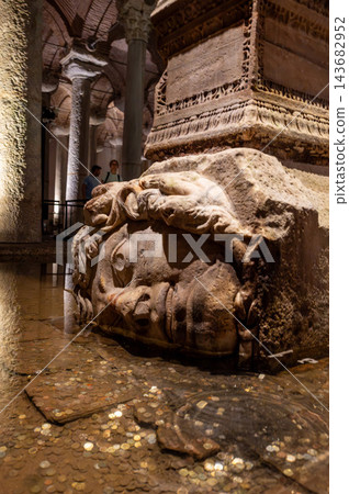 Istanbul,turkey,august 6, 2025. Medusa head sculpture supporting a column, surrounded by wishing coins in the ancient underground basilica cistern, istanbul, turkey 143682952