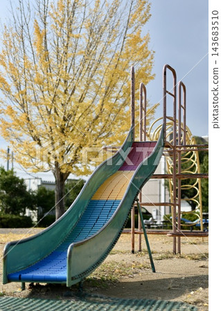 秋日公園裡色彩繽紛的滑梯和樹葉泛黃的樹木 143683510