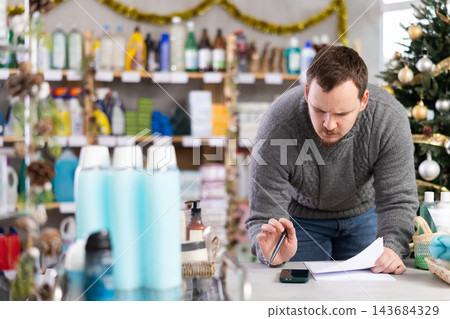 Male businessperson with paper document, plans to replenish restock stores inventory on Christmas Eve Male businessperson with paper document, plans to replenish restock stores inventory on Christmas Eve 143684329