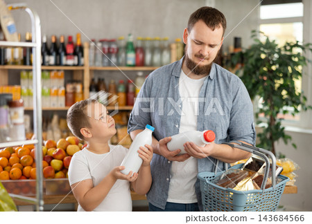 Preteen boy with father choosing bottled milk in grocery store Preteen boy with father choosing bottled milk in grocery store 143684566