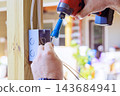 An electrician uses cordless drill to secure wiring in an open outlet box indoors. 143684941
