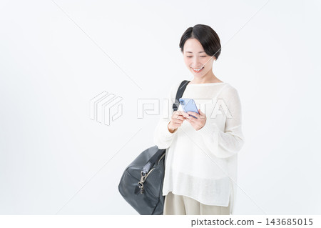 A woman going out with a large bag and her smartphone A woman going out with a large bag and her smartphone 143685015