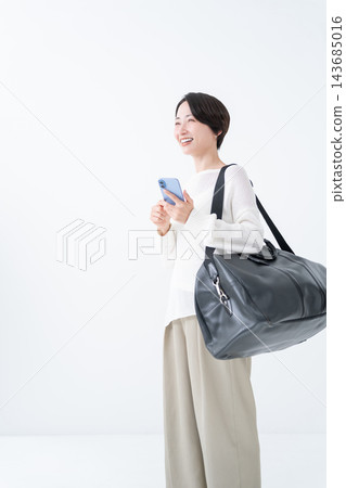A woman going out with a large bag and her smartphone A woman going out with a large bag and her smartphone 143685016