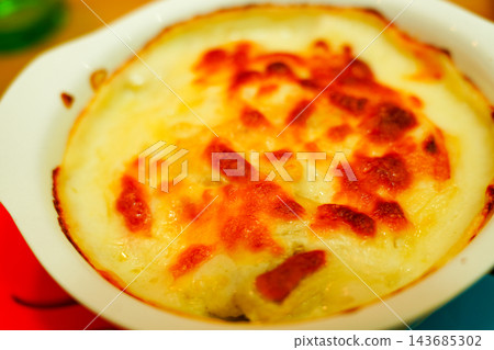 一份新鮮出爐的焗烤菜餚,上面鋪滿了奶酪,邊緣呈金黃色,看起來十分美味。 一份新鮮出爐的焗烤菜餚,上面鋪滿了奶酪,邊緣呈金黃色,看起來十分美味。 143685302