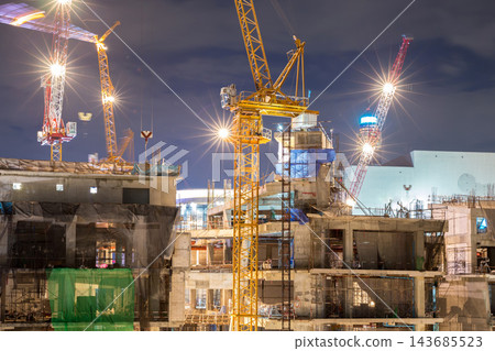 Construction Site with Tower Cranes and Bright Lights at Night Construction Site with Tower Cranes and Bright Lights at Night 143685523