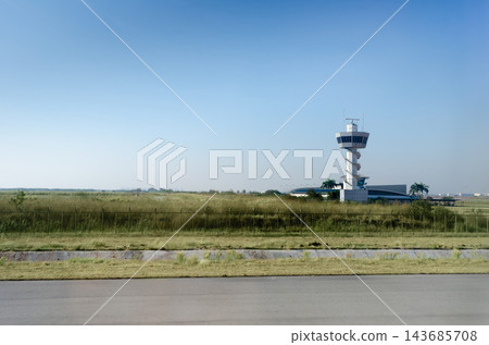 Airport Control Tower with Wide Blue Sky and Open Airfield Landscape Airport Control Tower with Wide Blue Sky and Open Airfield Landscape 143685708