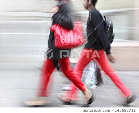 Motion Blur of Women Walking on Urban Sidewalk Motion Blur of Women Walking on Urban Sidewalk 143685711