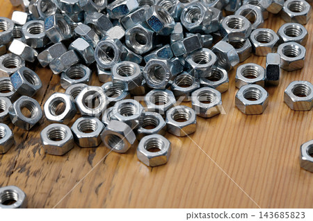Metal Hex Nuts on Wooden Workbench, Industrial Hardware Close-Up 143685823
