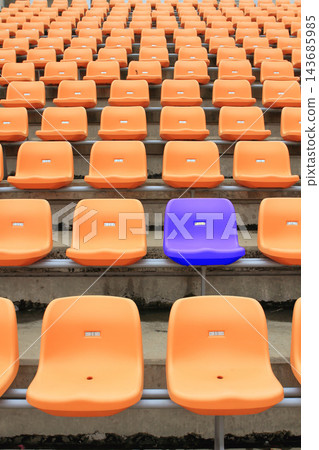 Empty Stadium Seats with One Purple Chair Among Orange Rows Empty Stadium Seats with One Purple Chair Among Orange Rows 143685985