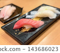Medium fatty tuna nigiri sushi. A Japanese dish made with fresh medium fatty tuna sashimi and vinegared rice. With squid nigiri sushi in the background. 143686023