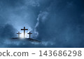 Three wooden crosses standing on a hill under a dramatic, cloudy blue sky with a glowing light behind them, symbolizing crucifixion and religious faith. Concept of Christian 143686298
