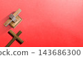 Two wooden Christian crucifixes resting on a vibrant red background, symbolizing faith, religion, and spirituality with a minimalist composition and ample negative space. Concept of Christian 143686300