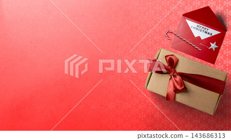 Christmas composition with a craft gift box tied with a red ribbon and an envelope with a Merry Christmas card on a red background. Concept of Merry Christmas Christmas composition with a craft gift box tied with a red ribbon and an envelope with a Merry Christmas card on a red background. Concept of Merry Christmas 143686313