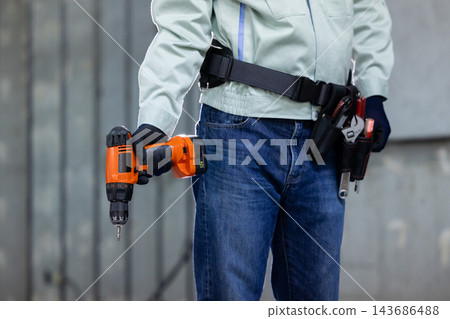 一名男子在建築工地上拿著工具。 一名男子在建築工地上拿著工具。 143686488