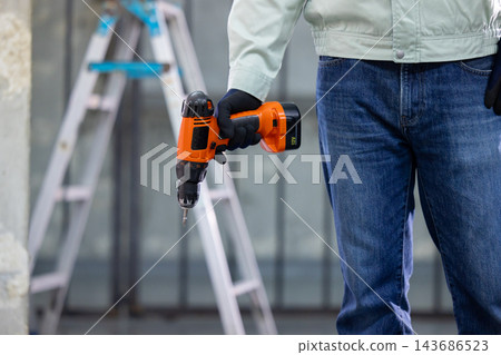 一名男子在建築工地上拿著工具。 一名男子在建築工地上拿著工具。 143686523