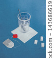 Glass Cup and Used Tea Bag on a Blue Textured Background 143686619