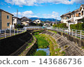 A small river and bridge flowing through a residential area, a scene on a sunny day. 143686736
