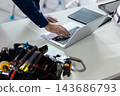 A male worker's hands operating a computer at a construction site. 143686793