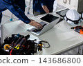 A construction site: A worker's hands as he conducts a meeting on his computer. 143686800