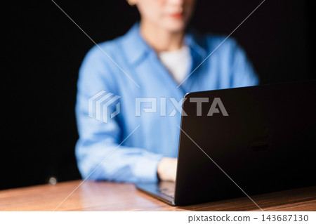 一個女人在黑暗的房間裡使用電腦 一個女人在黑暗的房間裡使用電腦 143687130