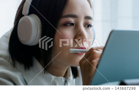 一位戴著耳機的女士正在使用平板電腦處理一個專案。 143687298