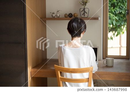 一位看起來像是自由工作者的日本女性,在她明亮時尚的家中,倚窗使用筆記型電腦工作。 一位看起來像是自由工作者的日本女性,在她明亮時尚的家中,倚窗使用筆記型電腦工作。 143687998